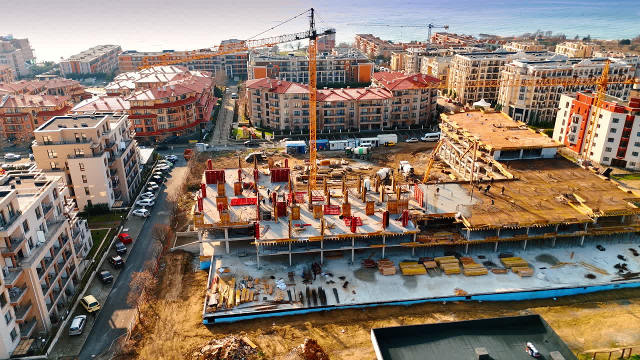 Prospettiva aerea di uno sviluppo residenziale con gru a torre. Vista di un edificio in costruzione con affaccio sul mare.