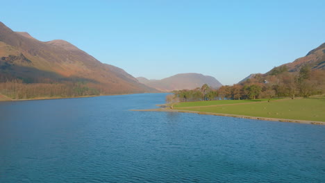 BUTTERMERE-Lake-District-Unesco-National-Park,-Aerial-Sunrise-push-forward-over-lake-with-trees-and-mountains-Mavic-3-Cine-Prores-422---Clip-2