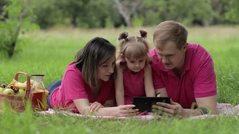 Family-weekend-picnic.-Daughter-child-girl-with-mother-and-father-browsing-on-internet-on-tablet