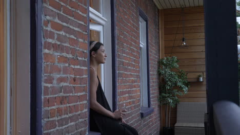 smiling woman sits on window sill of a trendy city apartment