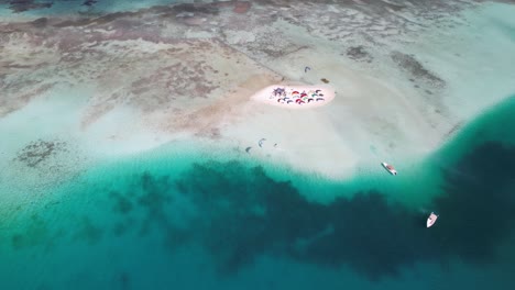 Dolly-Aéreo-Abajo,-Gente-En-Una-Pequeña-Isla-De-Vacaciones-De-Deportes-Acuáticos-En-El-Mar-Caribe