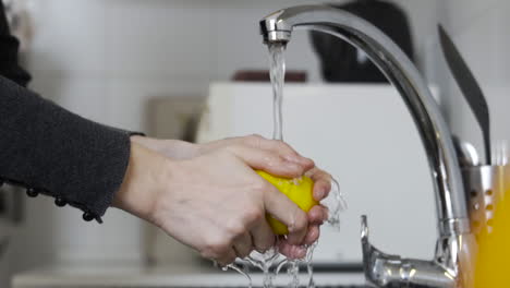 Manos-Lavando-Un-Limón-Amarillo-Con-Agua-Del-Grifo-En-La-Cocina-Sobre-El-Fregadero