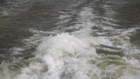 a speed boat and its engine propellers churn the water into high waves