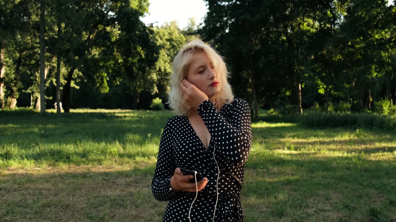 Drømmende smuk pige lytter til musik i parken