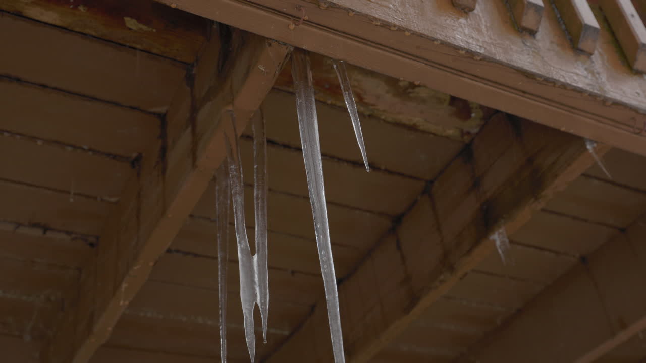 Handheld shot of melting icicles hanging from a balcony