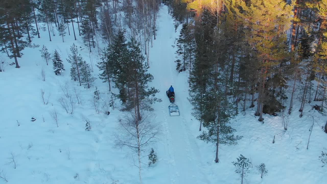 Attrezzatura per la creazione di piste da sci attaccata a una motoslitta nella foresta in inverno