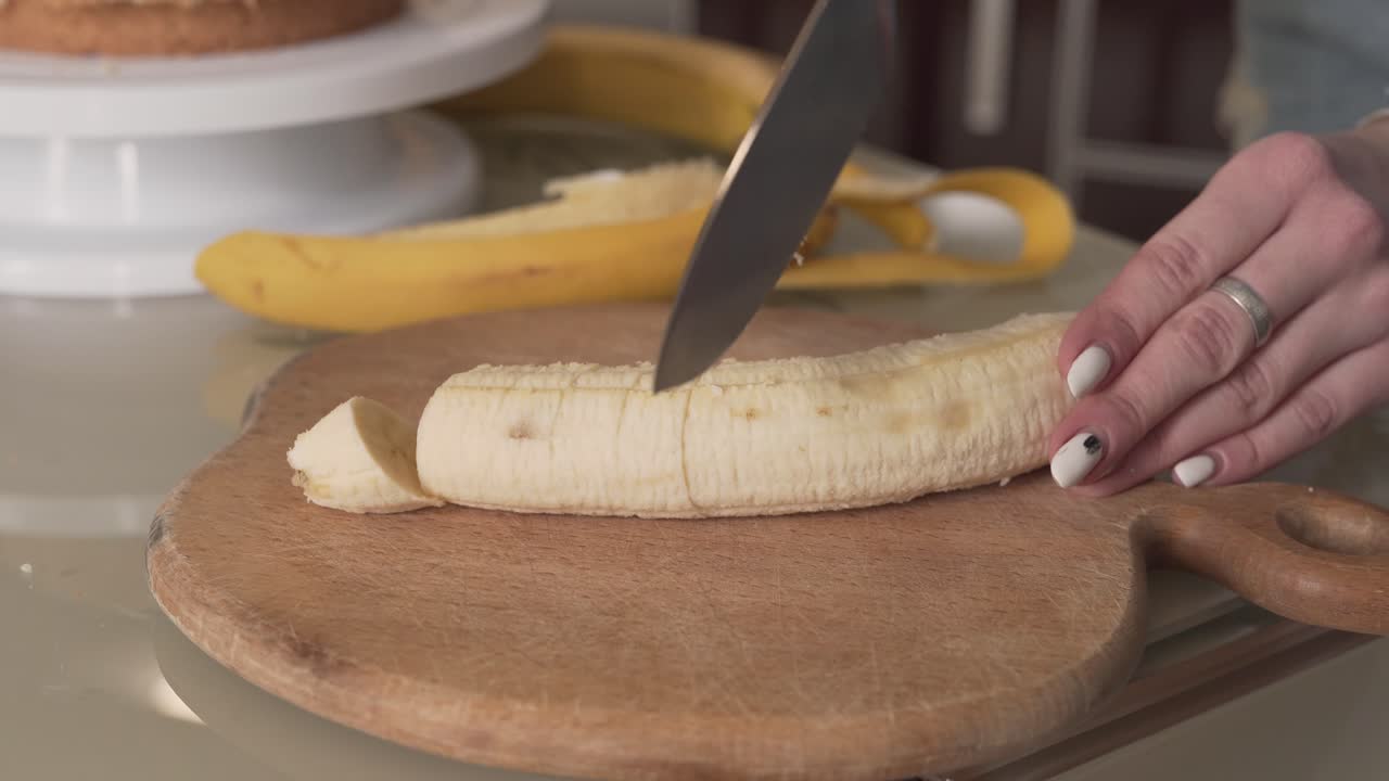 video de primer plano de una mujer que está cortando un plátano para un delicioso pastel futuro
