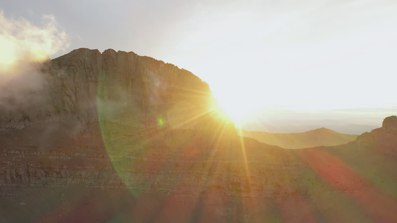 Drone shot capturing the sun emerging behind the Throne of Zeus on Mount Olympus, Greece during sunset