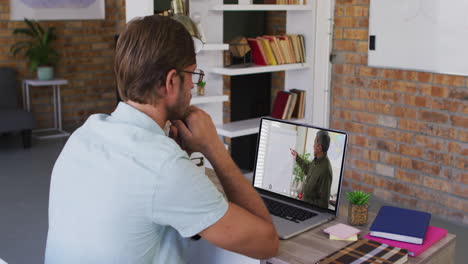 estudiante caucásico usando una computadora portátil en una videollamada con un profesor masculino