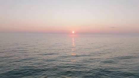 Beautiful-aerial-view-of-vibrant-high-contrast-sunset-over-calm-Baltic-sea,-clouds-at-the-horizon,-Karosta-war-port-concrete-coast-fortification-ruins-at-Liepaja,-drone-shot-moving-backward-low