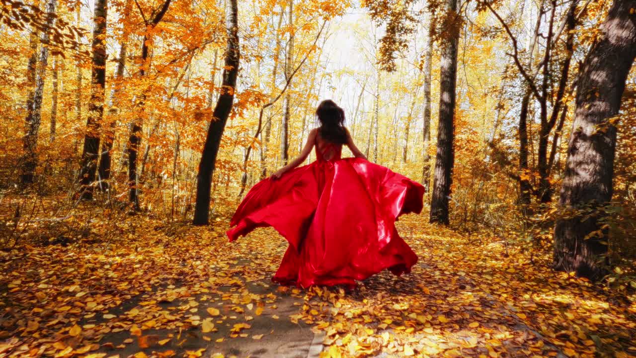 A Woman in a Flowing Red Dress Walks Through a Vibrant Autumn Forest, Surrounded by Golden Leaves and Radiant Fall Colors, Capturing the Essence of Seasonal Beauty