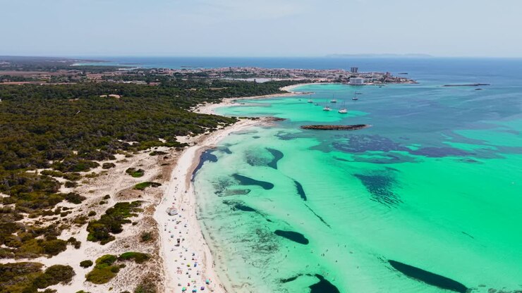 Vista aerea di una bellissima spiaggia con acqua turchese e una città sullo sfondo