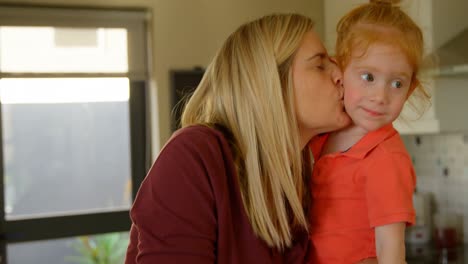 Mother-kissing-her-son-in-kitchen-at-home-4k