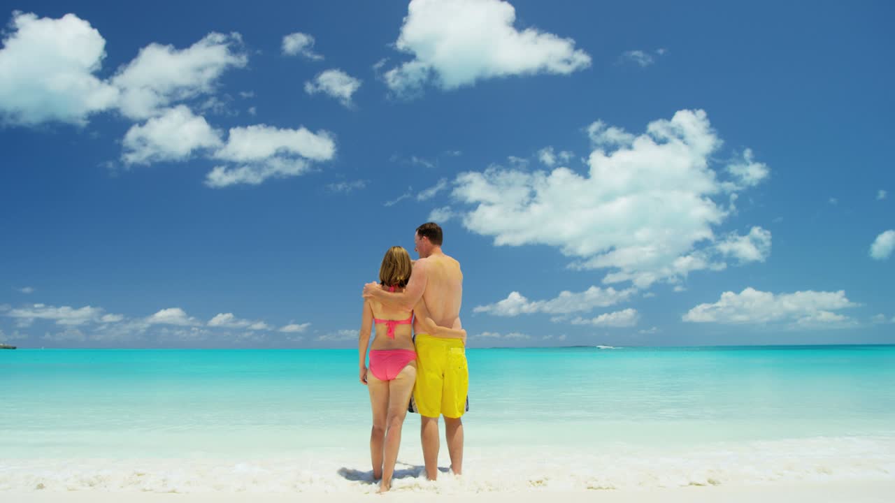 pareja caucásica descalza en trajes de baño en una playa tropical