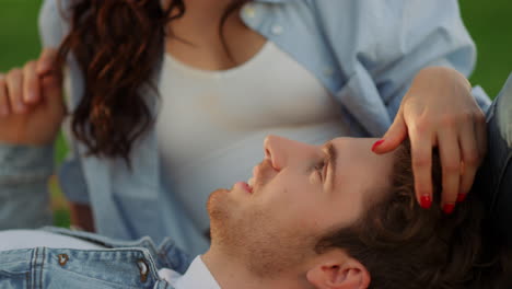 chica morena acariciando el cabello de un hombre al aire libre. hombre y mujer acostados en el suelo