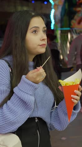 young woman eating french fries at a fair