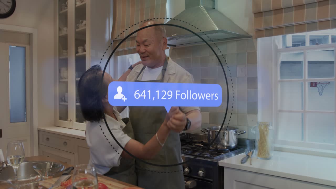 Couple cooking in kitchen noticing floating social fans graphic pulsing, numbers climbing embracing