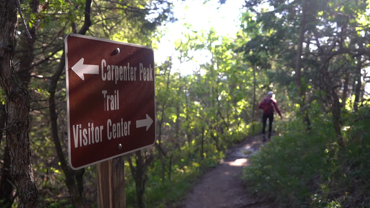 Roxborough State Park, Colorado USA, Carpenter Peak and Visitor Center Sign With Directions and Female Hiker on Trail in Forest, Full Frame Slow Motion