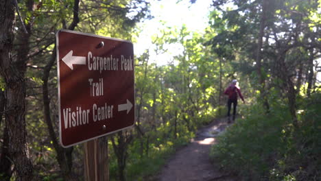 roxborough state park, colorado usa, carpenter peak and visitor center sign with directions and female hiker on trail in forest, full frame slow motion