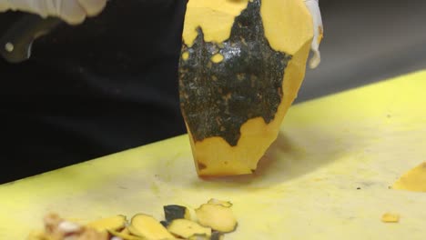 close up of chef hands preparing pumpkin for cooking, remove pumpkin peel with knife on the cutting board