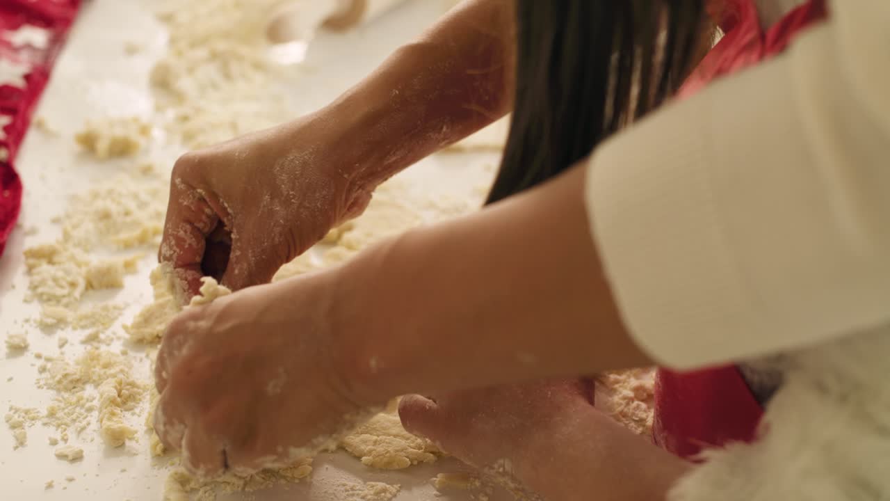 Handheld view of child using a cookie cutter while baking