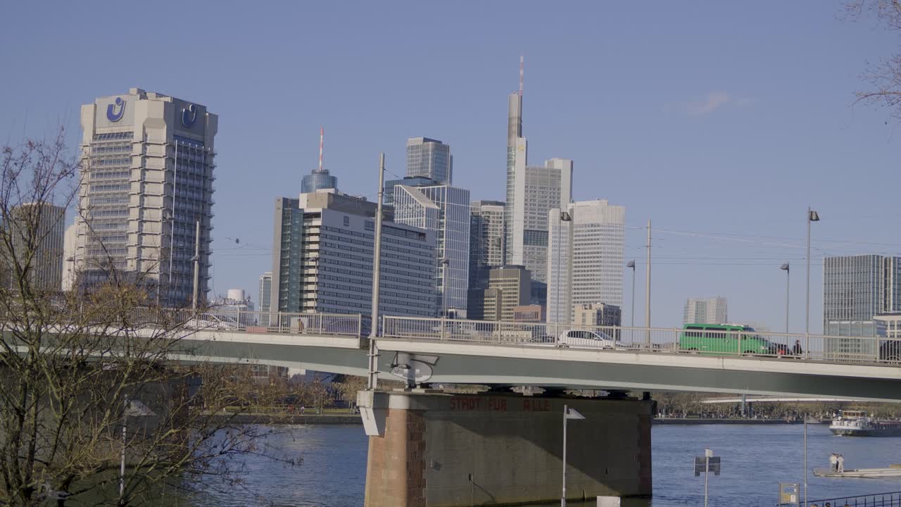 A bridge over the river with a view of Frankfurt’s modern skyline and tall buildings