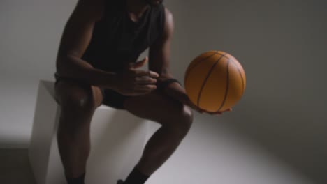 disparo de estudio de cerca de un jugador de baloncesto sentado lanzando la pelota de una mano a la otra