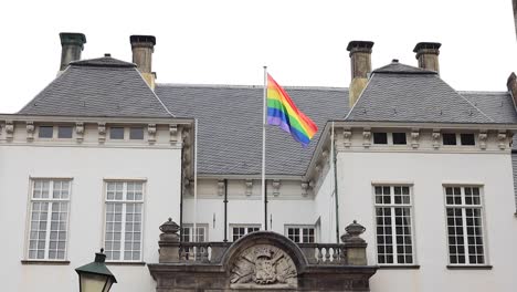 rainbow colored lgbtq+ flag on top of historic facade of city hall in zutphen, the netherlands, waving gently in support of community