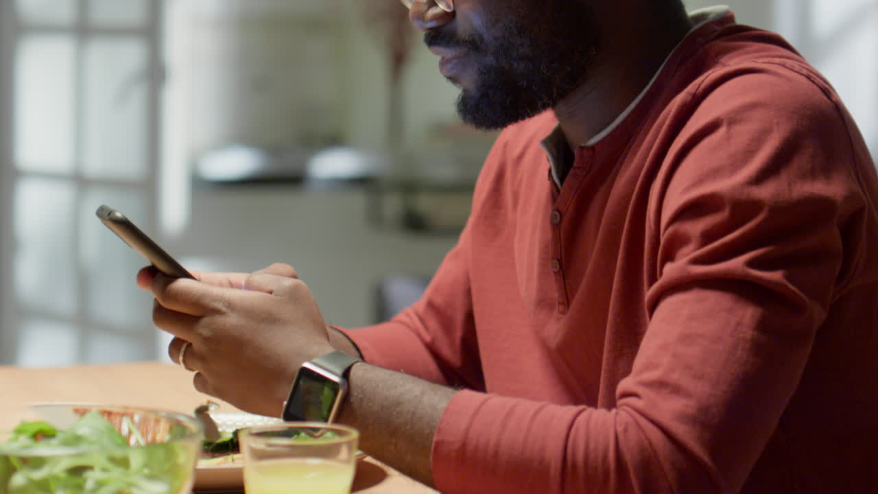 African American Man Using Smartphone during Dinner