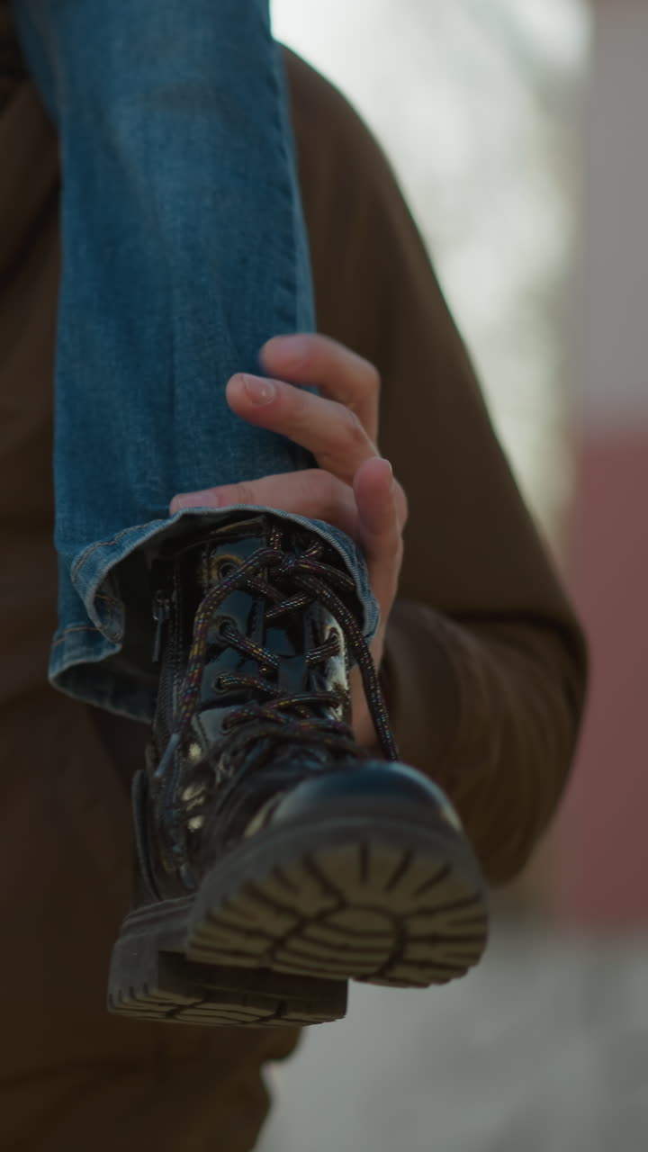 un niño se sienta en el cuello de un hombre, mostrando sólo sus piernas. el niño lleva pantalones vaqueros azules y botas negras, con el hombre sosteniendo sus piernas