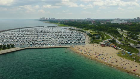 aerial view of crowded beach next to harbor on lake michigan