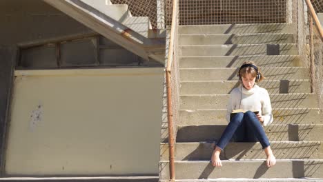 girl listening music while reading a book at beach 4k