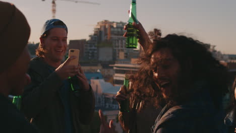 group of diverse friends hanging out dancing together mixed race man enjoying rooftop party dance music at sunset drinking having fun on weekend gathering