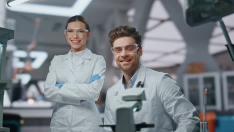 científicos sonrientes mirando la cámara en un laboratorio moderno de cerca. dos investigadores