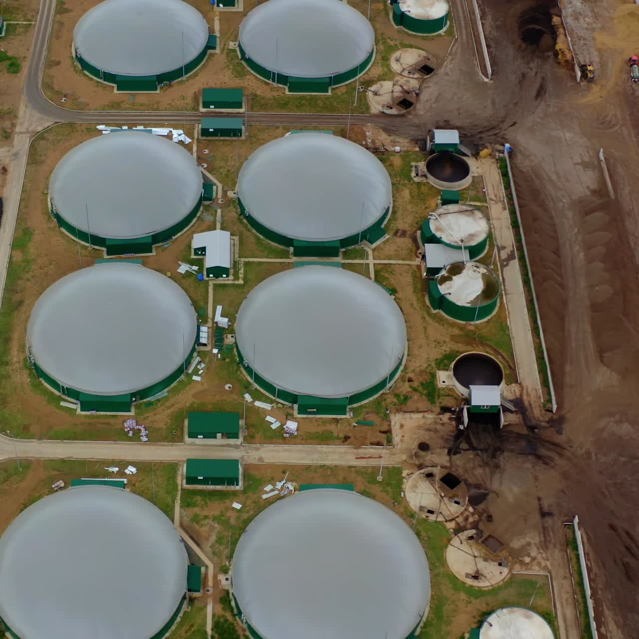 Modern biogas plant on field. Flying over the storage tanks for biomass production. Environmentally friendly biogas plant. Top view.