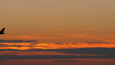 Silueta-Negra-De-Avión-Volando-Contra-El-Cielo-Nocturno-Dorado