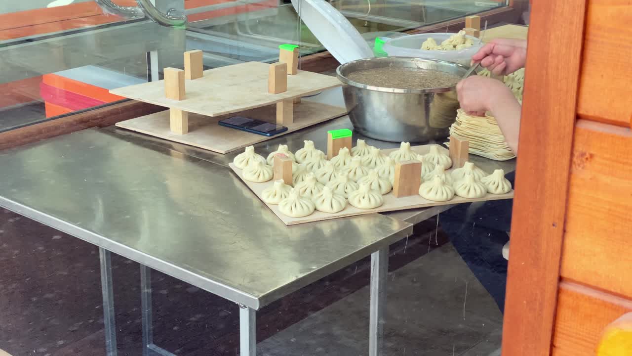 Chef cook make khinkali on silver table. Process and preparation georgian meal. food concept. Khinkali traditional georgian meal preparation in restaurant. Woman check her phone at work in restaurant on food preparation