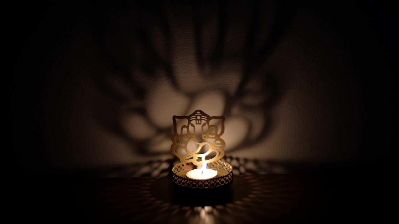 Static shadow and light dance, play reflection on wall of Ganesha cutout, also Ganapati Vinayaka, one of the best-known and most worshipped deities in the Hindu pantheon, specially during Diwali