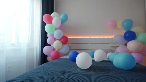 bed in bedroom decorated with colorful balloons, apartment bedroom interior. romantic date and holidays background.