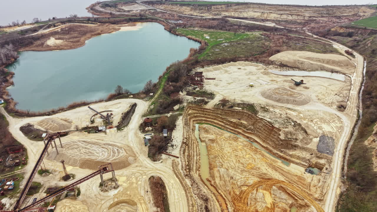 Sand excavation site near a lake with machinery and uneven land