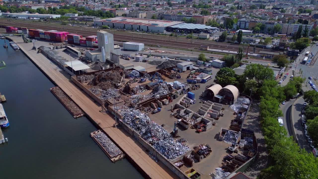 metal scrap yard, showing workers sorting and managing waste materials for recycling purposes near a city. Nice aerial view flight static tripod hovering drone