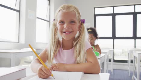 Video-of-happy-caucasian-girl-sitting-at-school-desk-and-learning