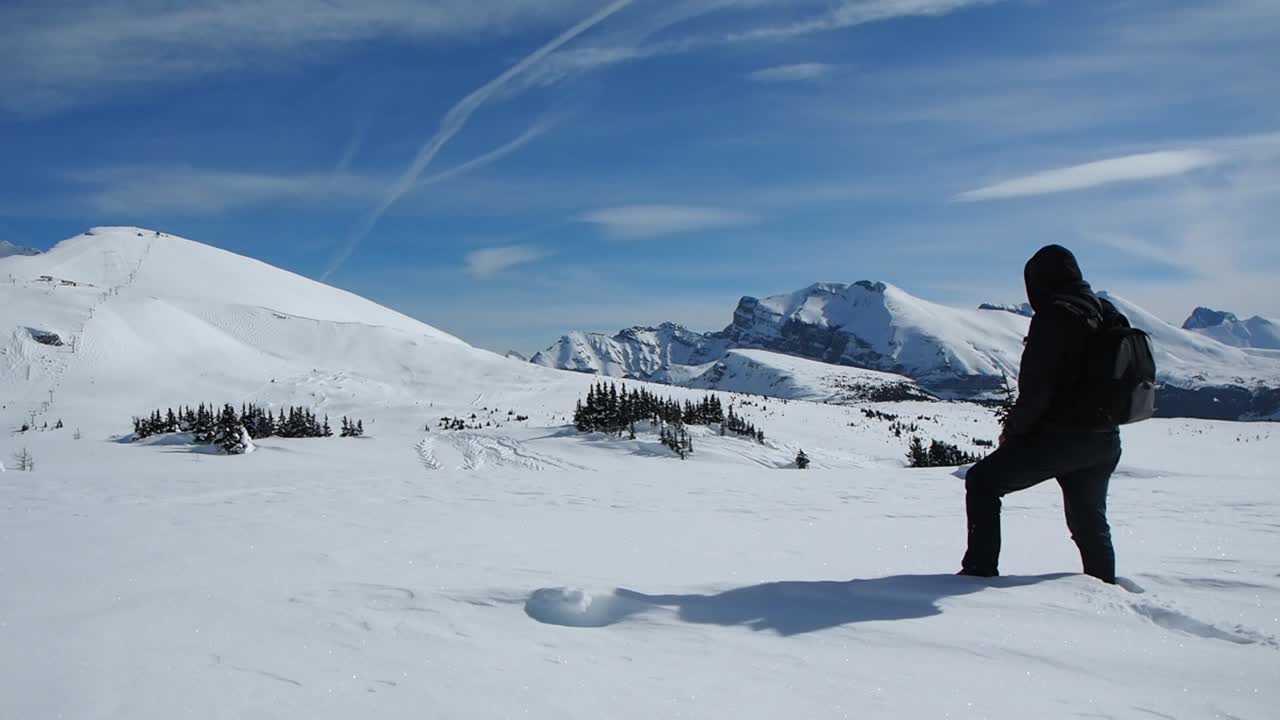 Uomo che cammina sulla neve in cima a una montagna