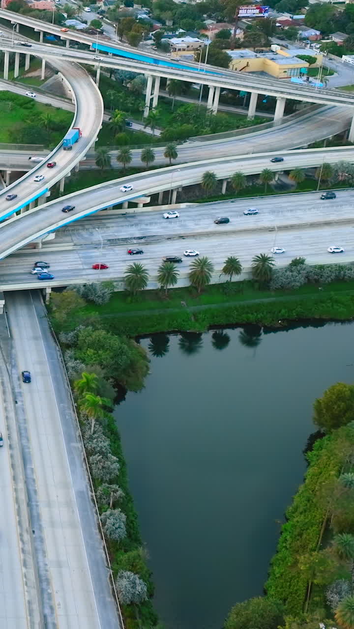 Multilevel interchange with cars and road signs. Aerial view of the evening streets of Miami with water. Vertical video