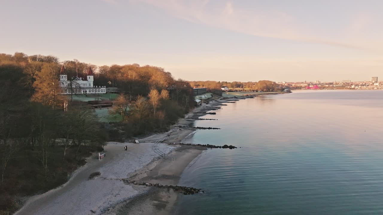 Filmagem com drone da mansão Varna e da floresta de Marselisborg no final do outono, perto de Aarhus, Dinamarca. Árvores desnudas e luz costeira suave capturam uma atmosfera nórdica tranquila