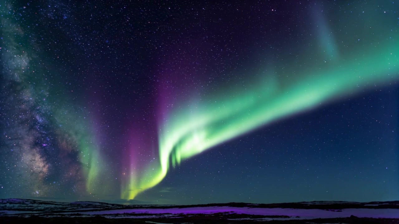Aurora boreale che si dispiega, dipingendo il cielo notturno con la Via Lattea sopra la tundra, con l'arrivo del vento solare.