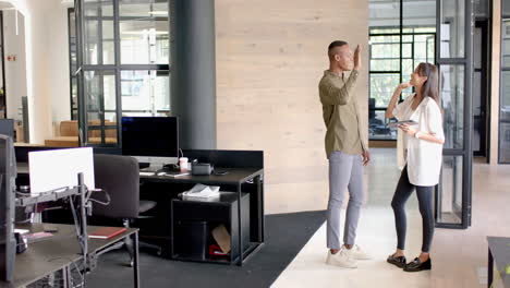 high-fiving, business colleagues celebrating success in modern office