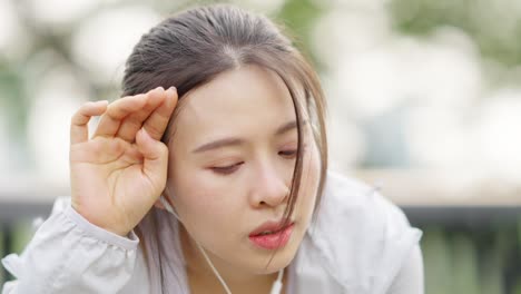 4k 아시아 여성이 아침에 공원에서 조하는 동안 음악을 듣고 있습니다.
