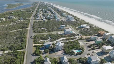 Aerial-of-Beach-at-Cape-San-Blas,-Florida-following-vehicles-traveling-along-main-road