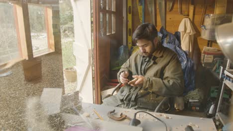 Male-carving-wood-at-home-in-his-outside-shed